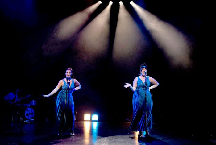 Four women in blue gowns singing onstage