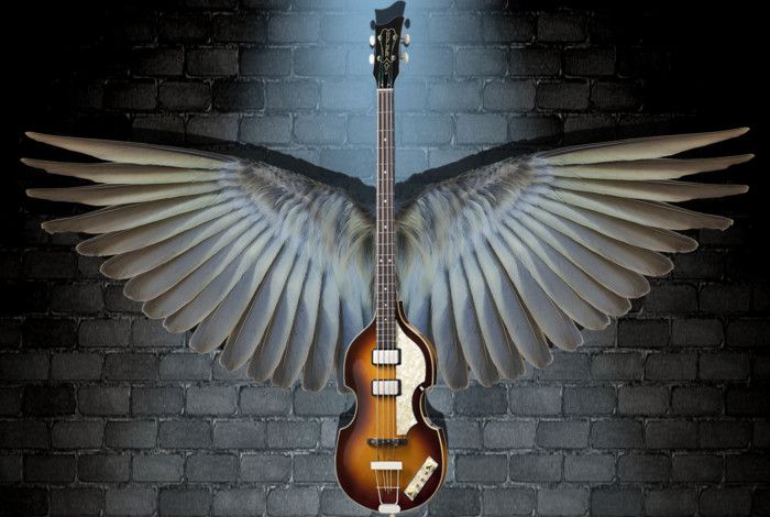 Guitar with wings against a brick wall.