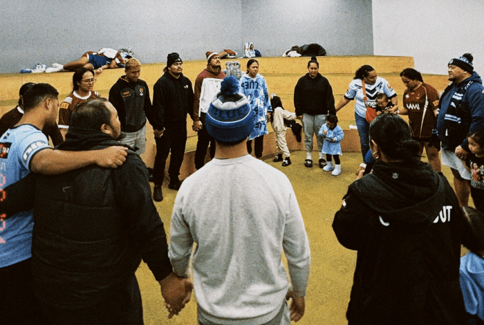 A group of people standing in a circle, some hugging