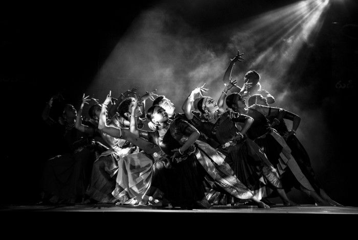 Black and white image of traditional Indian dancers in formation, dressed in traditional attire