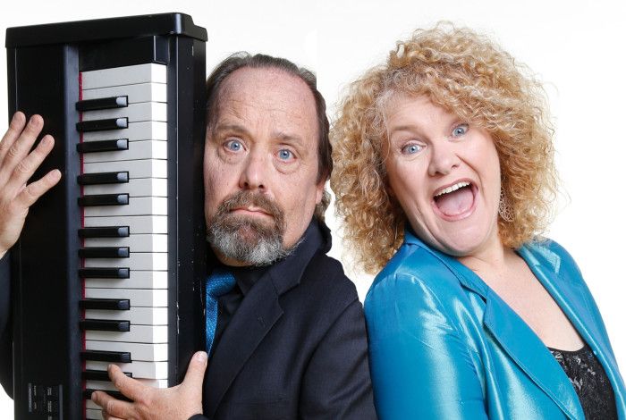 A man holding a piano with a lady that is laughing