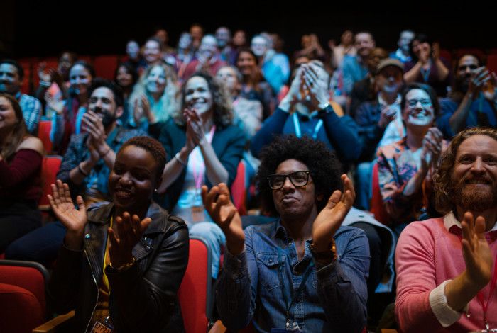 An audience claps and enjoys a performance in a theatre