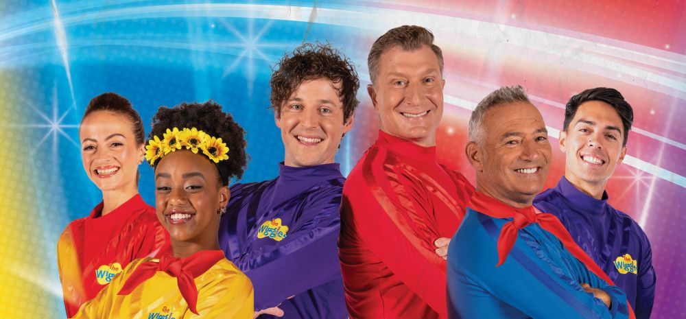 Brightly coloured image of The Wiggles, posing with their arms crossed and smiling