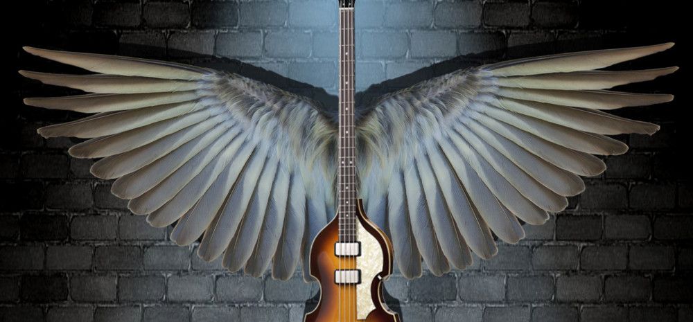Guitar with wings against a brick wall.