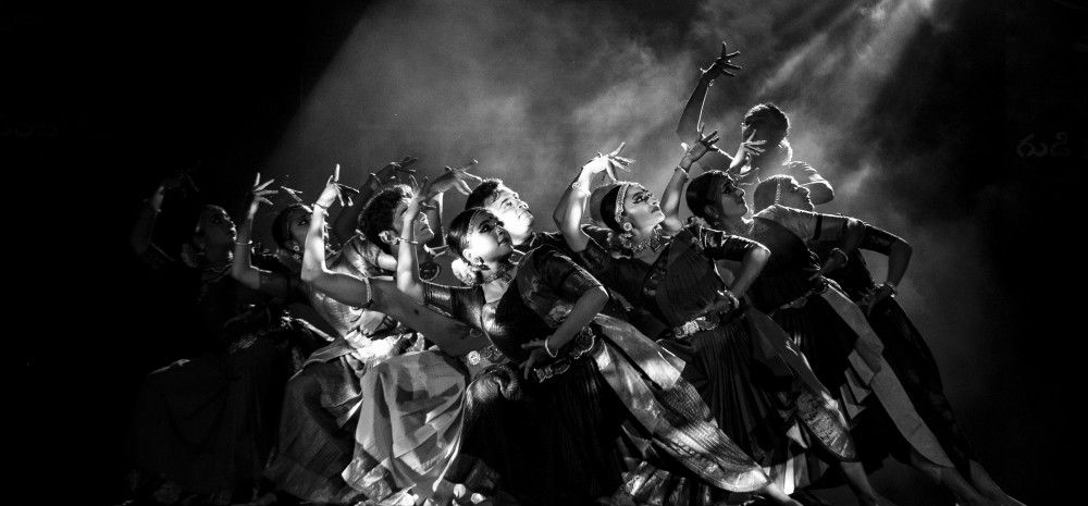 Black and white image of traditional Indian dancers in formation, dressed in traditional attire