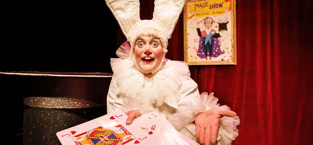 Person dressed as rabbit holding giant playing cards