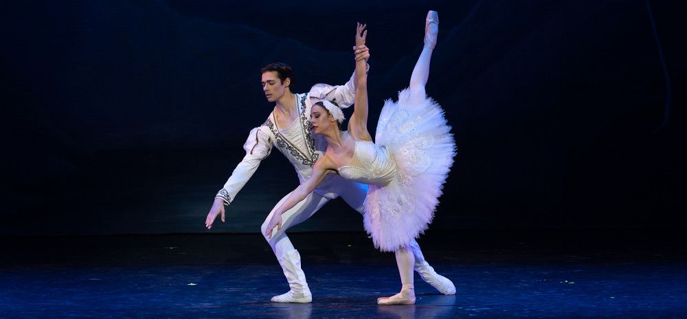Two people doing ballet moves on stage