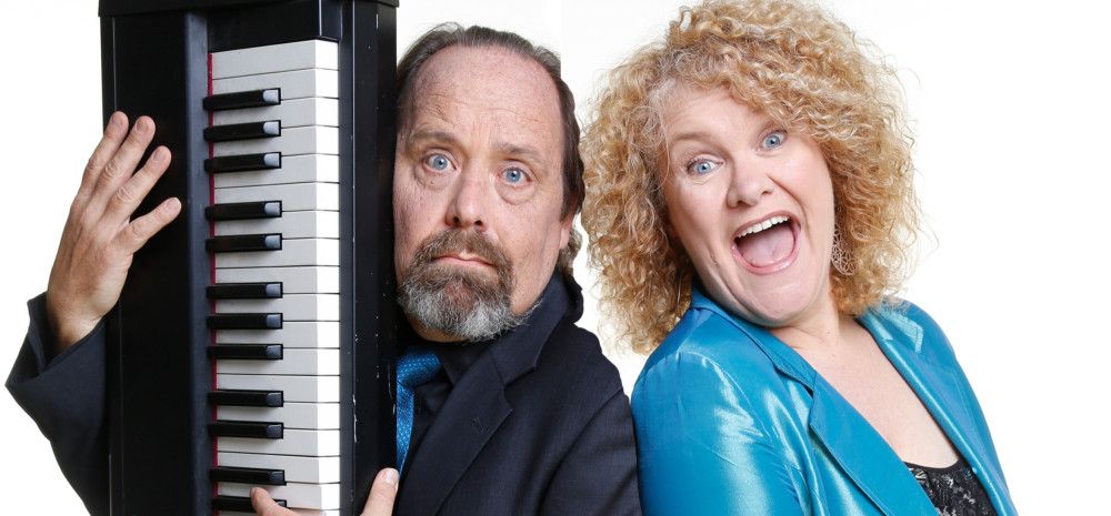 A man holding a piano with a lady that is laughing