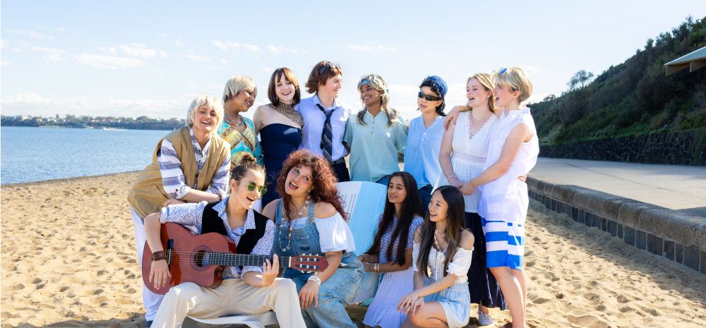 People huddled together singing on a beach.
