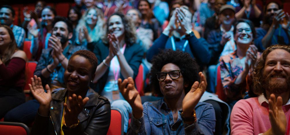 An audience claps and enjoys a performance in a theatre