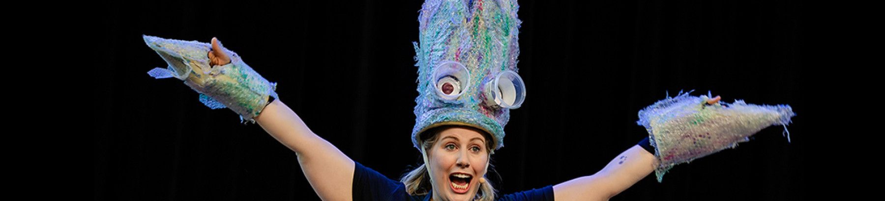 A person performing with puppets on her head and hands